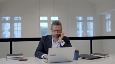 Ofiste çalışan biri telefonla konuşuyor. Takım elbiseli patron telefonda konuşuyor. Telefon görüşmesi. Telefon kullanan bir iş adamı. CEO akıllı telefondan sohbet ediyor. İş konuşmaları. Akıllı telefondan sorunları çözen adam