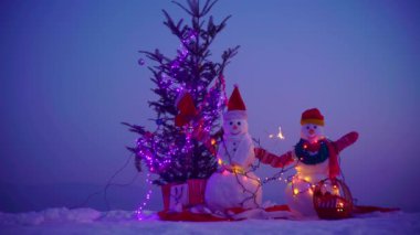 Mutlu Noeller ve mutlu yıllar. Gece kışında kardan adam. Karlı bir kış gecesinde kardan adam. Işıklı Kardan Adam Noel 'i. Geceleri kardan adam figürleri. Evin yakınındaki Noel süsleri.