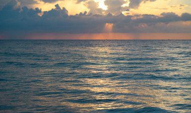 Gün batımı deniz manzarası. Sakin dalgalarla renkli sahil gündoğumu. Doğa deniz göğü. Mavi gökyüzüne ve denize karşı farklı renkte bulutlarla gün doğumu. Altından dramatik gökyüzü manzaralı deniz üzerinde gün batımı