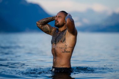 Kaslı adam gölde suda rahatlıyor. Deniz suyunda seksi erkek modeli. Yakışıklı çocuk Alps gölü suyunda dinleniyor. Seksi, ıslak erkek gövdesi, damlalık suda. İnsan özgürlüğü yaşam tarzı. Güçlü kaslı adam.