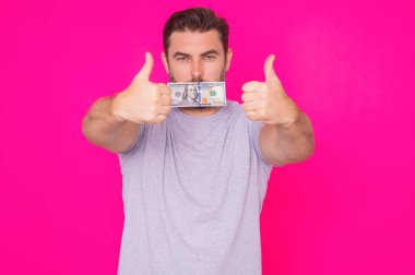 Orta yaşlı İspanyol adam, izole edilmiş pembe arka planda nakit para tutuyor. Dolar banknotları olan bir iş adamının stüdyo portresi. Dolar parası konsepti. Kariyer zenginliği işi