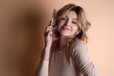 Saçını tarayan bir kadın. Sağlıklı ve temiz saçlara önem verir. Güzellik kuaförü konsepti. Stüdyoda taraklı bir kız. Taranmış saçlar, yumuşak yumuşak ipeksi saçlar keratin etkisi yapar. Saç fırçası