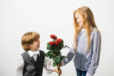 Genç kız arkadaşı için gül taşıyan küçük çocuk, romantik çocuklar, beyaz arka planda soyutlanmış. Romantik, erkek ve kız aşk ve romantizm için çiçek veriyor.