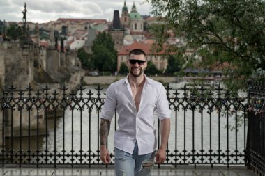 Seksi yakışıklı adamın portresi. Hippi adam dışarıda modellik yapıyor. Şehirde güneş gözlüklü genç bir moda adamı. Kendine güvenen erkek model. Adam gururlu görünüyor. Avrupa caddesinde çekici bir adam. Zarif adam.