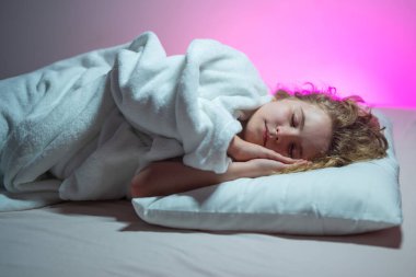 Çocuklar için yastık ve battaniye. Küçük çocuk uyuyor. Sevimli çocuk yatakta uyuyor. Uyuyan çocuk. Çocuk karanlık odada uyuyor. Evdeki bir yatakta uyuyan çocuk