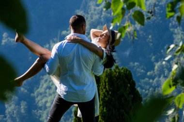 Adam kadını güvenli bir şekilde kollarında tutuyor. Kaygısız ve derinden aşık olan çift, birbirlerine eşlik etmekten hoşlanıyordu. Yaz doğasına aşık romantik çift. Onu zahmetsizce taşıyor.