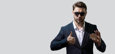 Elinde kredi kartı olan yakışıklı bir adam, fotokopi alanı olan bir afiş. Gri stüdyo geçmişinde kredi kartı olan orta yaşlı bir adam. Takım elbiseli bir işadamı kredi kartıyla ödeme yapıyor.