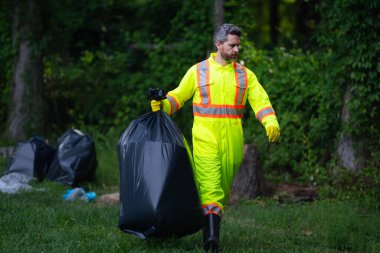 Gönüllü, çöpleri toplamaya yardım eder. Kirli orman. Çöp yığını. Gezegen kirliliği çevre koruma kavramı. Ormanı temizliyorum. Çöp torbalarına çöp koymak, çevre koruma