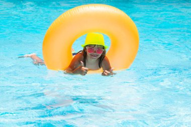 Çocuk havuzda oynuyor. Yaz tatili kavramı. Yaz çocukları plajdaki deniz suyunda yüzen yüzükle portre yaparlar.