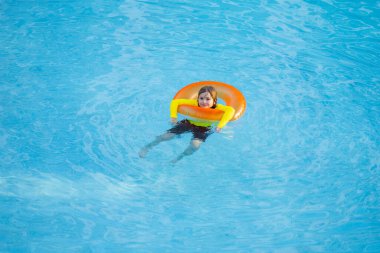 Çocuk şişme yüzükle bilardo oynuyor. Yüzme havuzunda şişme yüzüğü olan çocuk. Çocuk oyuncakları. Çocuklar tropikal tatil köylerinde oynarlar. Çocuk havuzda oynuyor. Yaz tatili kavramı