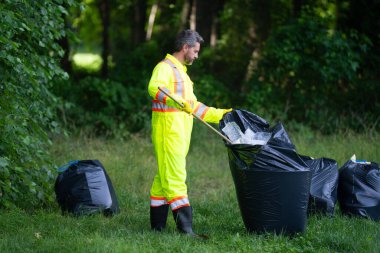 Çevre plastik kirliliği. Ormanda çöp toplayan ve elinde çöp torbası tutan bir gönüllü. Çevresel koruma. Çevre aktivisti. Çevre koruma ve atık kirliliği