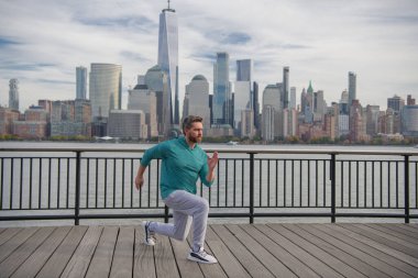 Spor adamı New York 'ta antrenman yapıyor. Erkek sporcu kardiyo sağlığı için antrenman yapıyor. Spor salonu açık havada. Adam dışarıda çalışıyor. New York 'ta bacak çalıştıran adam kaslarını çalıştırıyor.