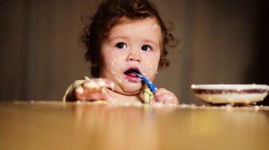 Bebek kaşıkla yiyor. Çocuk yemeğini ye. Çocuk maması yiyen aç küçük bir çocuk. Bebek yulaf lapası. Küçük bebek sağlıklı yiyecekler yiyor. Küçük bir bebek yemeğini yiyor. Komik çocuklar yüz ifadeleri