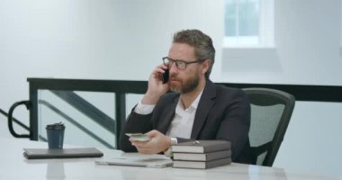 İş adamı telefonda konuşuyor. Ofiste dizüstü bilgisayarla çalışıyor. Ofiste çalışan bir çalışan. İş adamının telefon görüşmesi var. İş adamı telefonda konuşuyor. İş yerinde telefon kullanan bir iş adamı.