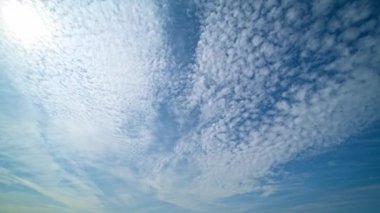 Gökyüzü zaman ayarlı. Hareket eden bulutlar ve güneş. Beyaz kabarık bulutlar mavi gündüz vakti gökyüzünde yavaşça süzülür. Güzel gökyüzü hareket ediyor. Beyaz kümülüs ve sirrus