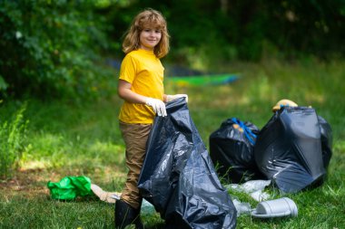 Çocuk dışarıda çöp topluyor. Ekoloji konsepti. Çevre kirliliği. Dünya Günü. Çöp tenekelerini geri dönüşümle temizleyin. Doğa temizliği. Çevre plastik kirliliği