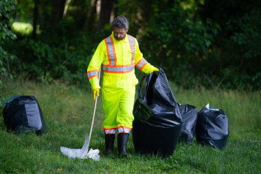 Gönüllü, çöpleri toplamaya yardım eder. Kirli orman. Çöp yığını. Gezegen kirliliği çevre koruma kavramı. Ormanı temizliyorum. Çöp torbalarına çöp koymak, çevre koruma