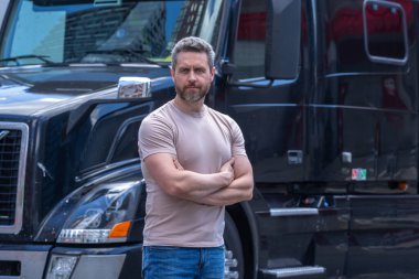 Kamyon şoförü. CDL. Kamyonun yanında erkek sürücü var. Kamyon şoförü. Milenyum kamyoncusu. Kamyon sahibi. Ulaşım endüstrisi araçları. Kamyonun önünde poz veren yakışıklı bir adam. Kamyon sürücüleri CDL