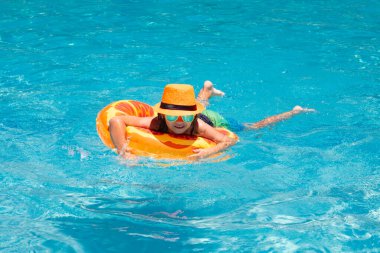 Summer rahatla. Çocuklar yüzme havuzunda yüzen yüzüklerle yüzerler. Çocuklar yaz tatili. Havuz başında şişme yüzüğü olan küçük mutlu çocuk.
