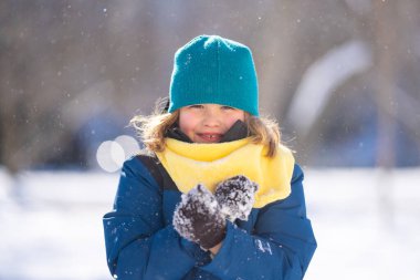 Çocuk kar yağışında karla oynuyor. Kartopu savaşı. Kışın giydiği elbiseli çocuk kartopu atıyor. Kış çocukları karla oynar. Çocuk kartopuyla oynuyor. Kış çocuğu suratı. Çocuk kartopu oynuyor.