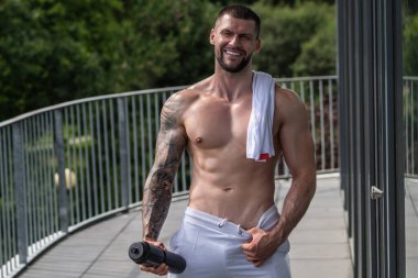 Egzersizden sonra güçlü bir genç adam. Spor kulübündeki erkek sporcu. Genç adamın fitness antrenmanı var. Teras yakınında poz veren erkek sporcu. İnsanlar spor ve sağlıklı yaşam tarzı konsepti