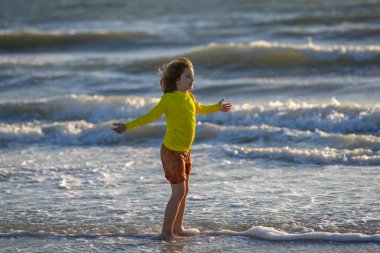 Denizde oynayan heyecanlı çocuk. Çocuk dışarıda eğleniyor. Yaz tatili ve sağlıklı yaşam tarzı konsepti. Yazın kumsalda eğlenen sevimli çocuklar. Denizde oynayan mutlu çocuk. Yaz tatili