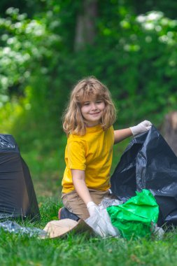 Çocuk dışarıda çöp topluyor. Ekoloji konsepti. Çevre kirliliği. Dünya Günü. Çöp tenekelerini geri dönüşümle temizleyin. Doğa temizliği. Çevre plastik kirliliği