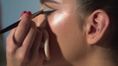 Makyaj sanatçısı kozmetik kullanıyor. Güzellik abidesi. Makyaj ustasının eli, genç güzel kızın dudaklarını boyuyor. Makyaj yapılıyor. Makyaj sanatçısı tarafından makyaj yapan güzel Asyalı bir kadın.