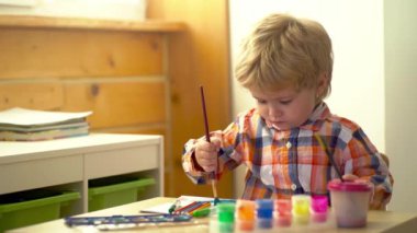 Anaokulu çocukları. Küçük şirin bir çocuk resmi ve çizimi. Pastel boyalı ve kağıda çizim yapan bir çocuk. Çocuklar için yaratıcı bir oyun. Suluboya kullanarak rengarenk boyalı bebek resmi.