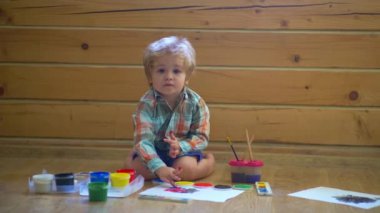 Küçük şirin bir çocuk resmi ve çizimi. Pastel boyalı ve kağıda çizim yapan bir çocuk. Yaratıcı düşünce ve çocukların sanatsal kavramları. Boya fırçası ve suluboya ile çocuk resmi. Bebek resmi