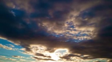 Güneş batıyor, bulutlar mavi ve turuncu dramatik gökyüzünde, güneş ışınlarıyla. Gece Günbatımı Gökyüzü zaman ayarlı. Gün batımında hareket eden bulutlar. Akşam bulutları. Alacakaranlık alacakaranlık gökyüzü zaman aşımı. Dramatik gökyüzü