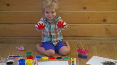 Küçük şirin bir çocuk resmi ve çizimi. Pastel boyalı ve kağıda çizim yapan bir çocuk. Yaratıcı düşünce ve çocukların sanatsal kavramları. Boya fırçası ve suluboya ile çocuk resmi. Bebek resmi