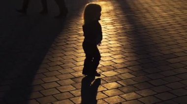 Küçük çocuk şehir caddesinde tek başına yürüyor. Kaldırımda tek başına yürüyen bir bebek. Çocuğun adımları. Şehir caddesinde yürüyen çocuk silueti. Çocuk yolda tek başına yürüyor.