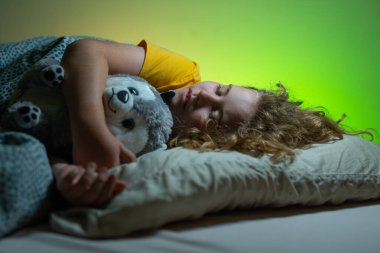 Çocuklar için yastık ve battaniye. Küçük çocuk uyuyor. Sevimli çocuk yatakta uyuyor. Uyuyan çocuk. Çocuk karanlık odada uyuyor. Evdeki bir yatakta uyuyan çocuk