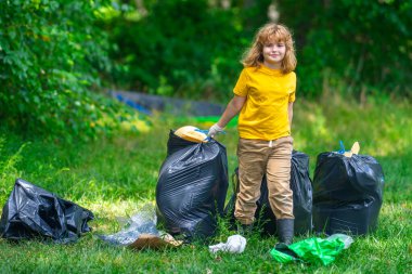 Çevre plastik kirliliği. Ormanda çöp toplayan ve elinde çöp torbası tutan gönüllü bir çocuk. Çevresel koruma. Çevre aktivisti. Çevresel koruma. Atık kirliliği