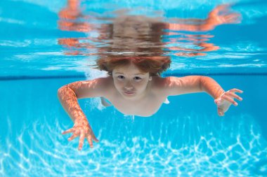 Çocuk yüzme havuzunda yüzer ve suya dalar. Yaz çocukları sahildeki deniz suyunda