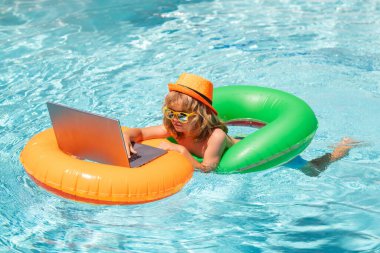 Laptop havuzlu şişme bir yüzükte yüzen bir çocuk. Yaz çevrimiçi teknoloji. Yaz tatilinde tropik deniz sahillerinde dinlenen bir gezgin. Seyahat, dizüstü bilgisayar kullanan çocuk.