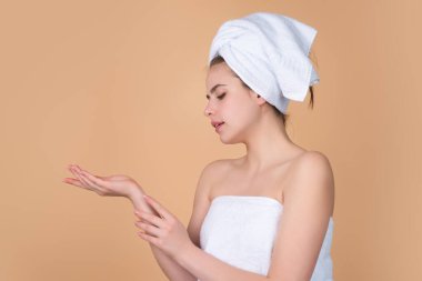 Young woman applying body cream against studio background. Beauty routine. Studio face of a beautiful woman with perfect skin. Wrinkle cream. Concept of beauty. Woman applying face cream