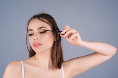 Kirpik makyajı. Kaş kalemi yakın plan ile kirpikleri şekillendiren güzellik modeli. Kadınlar kirpiklerini kirpikleriyle fırçalarlar. Doğal bir makyaj. Kirpik modelliği. Tarak kirpikleri