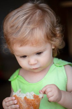 Kuru üzümlü rusk yiyen küçük bir çocuk. Çörek yiyen bebek. Yüzünü kapat. Sandviç yiyen tatlı çocuk, kendini besleme konsepti.