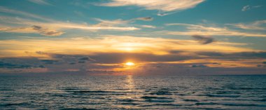 Tropikal deniz okyanusunda gün batımı ve gündoğumu bulutları. Seyahat tatili afişi. Manzara gökyüzü ve yansıma ışınları. Alacakaranlık, denizde alacakaranlık. Sakin, altın gökyüzü arka planı