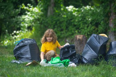 Lastik eldivenli çocuk çöp torbasıyla ormandaki çöpleri temizliyor. Eko, çevre koruma. Kirliliği geri dönüştür. Çocuk çöp ve plastik çöp topluyor. Ortamı kaydet