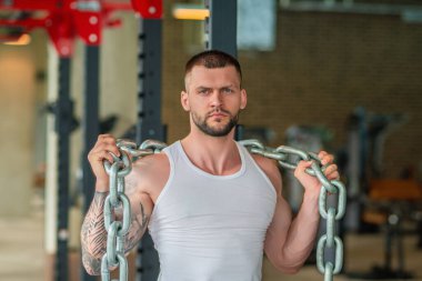 Ağırlık metal zincirlerle egzersiz yapan bir adam. Uygun model ağırlık kaldırma zinciri, spor salonunda egzersiz. Zincirlerle çalış. Güçlü, kaslı, formda, zincirleri ve ağır ağırlığı olan bir adam. Pazılar için alıştırmalar