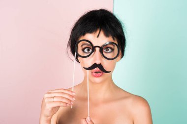 Young woman in black wig looking making fake mustache positive and happy. Funny Girl smile. Young transgender woman. Funny woman face. Portrait of attractive funny girl grimacing. Emotion woman clipart