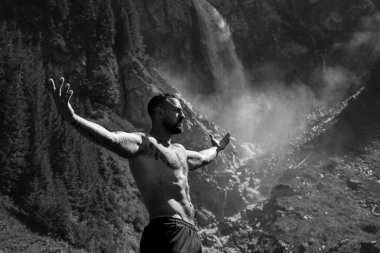 Yaz tatilindeki erkek turist. Yaz tatilinde çıplak gövdeli yakışıklı bir adam. Dışarıda seksi bir yürüyüşçü var. Şelale manzarasında yürüyen bir turist. İnsan Seyahati ve doğa