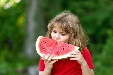 Çocukların yüzü karpuzla kaplı. Yazlık parkta karpuz yiyen komik çocuk. Çocuk, bebek, sağlıklı yemek. Bahçede karpuz yiyen bir çocuk. Çocuklar dışarıda meyve yer. Çocuk karpuz seviyor.