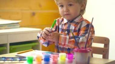 Anaokulu çocukları. Küçük şirin bir çocuk resmi ve çizimi. Pastel boyalı ve kağıda çizim yapan bir çocuk. Yaratıcı düşünce ve çocukların sanatsal kavramları. Boyalı fırça ve suluboya çocuk resimleri