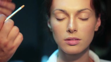 Makyaj sanatçısı göz farı sürüyor. Makyaj güzeli kadın gözleri. Yüz makyajını yakın plan yap. Makyaj modeli olan profesyonel bir makyöz. Moda gözlüklü güzel bir genç kadın.