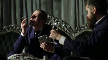 Amerikan para işi. Zengin beyefendi para sayar. Karanlık odada para sayan gangsterler. Zengin iş adamı. Zengin adam dolarları elinde tutar. 100 dolar içinde çok parası olan zengin bir adam.