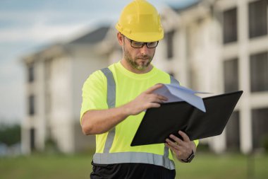 Dosyası olan mühendis, bina teftişi. İnşaat alanında çalışan bir inşaat işçisi. İnşaat alanında miğferi olan bir buider. İnşaat alanında çalışan bir işçi. Bilder in hardhat